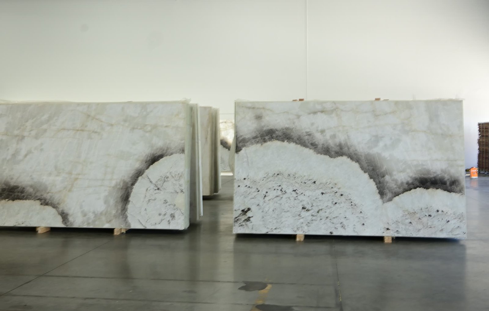 Two matching stone slabs standing side by side on the showroom floor, with further material stacked behind.
