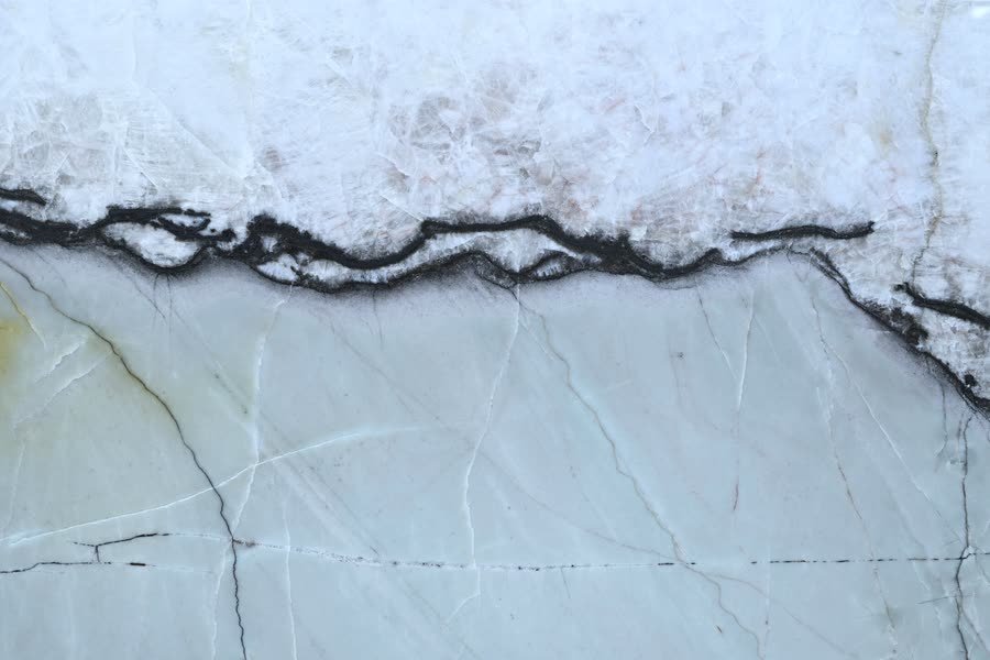Bonsai — close view of the stone surface. A pale ground crossed by a single dark banded seam.