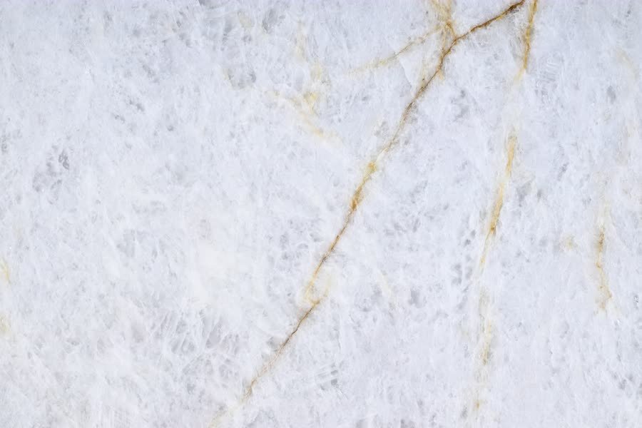 Crystallo Traslux — close view of the stone surface. Translucent white quartz threaded with warm gold seams.
