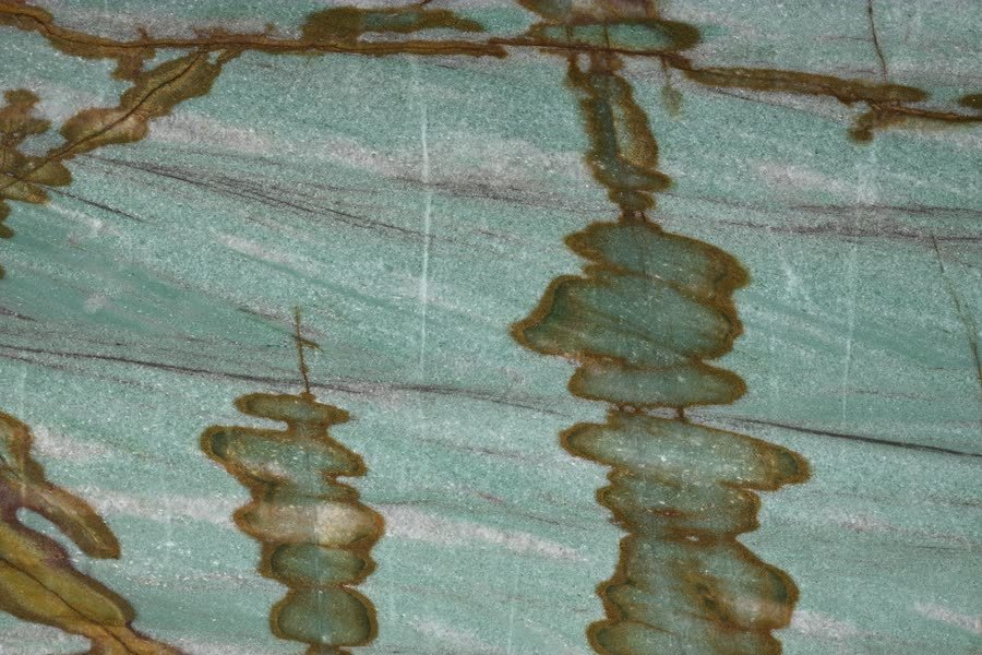 Sauipe — close view of the stone surface. Stacked amber formations banded in green and gold.