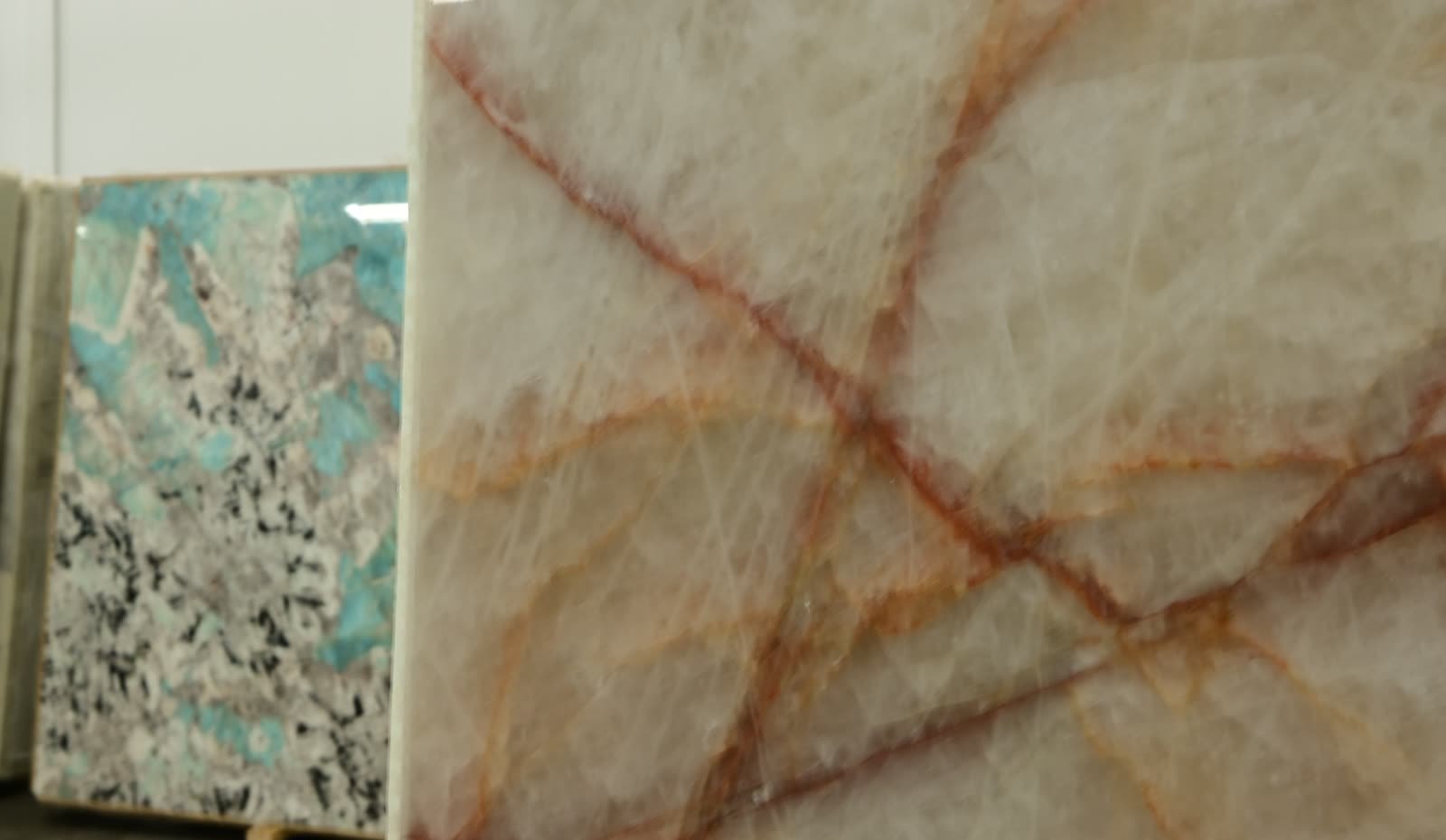 A stone slab face photographed close, its pale surface crossed by warm veining.