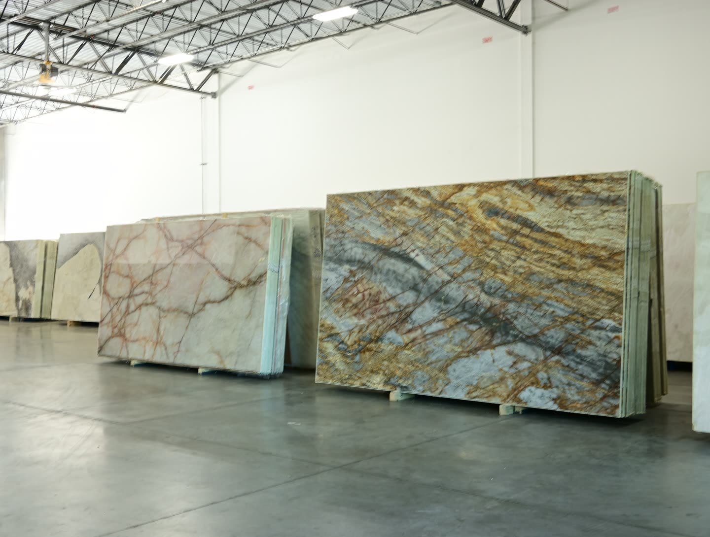 A slab with gold and blue-grey diagonal veining standing among other slabs on the showroom floor.