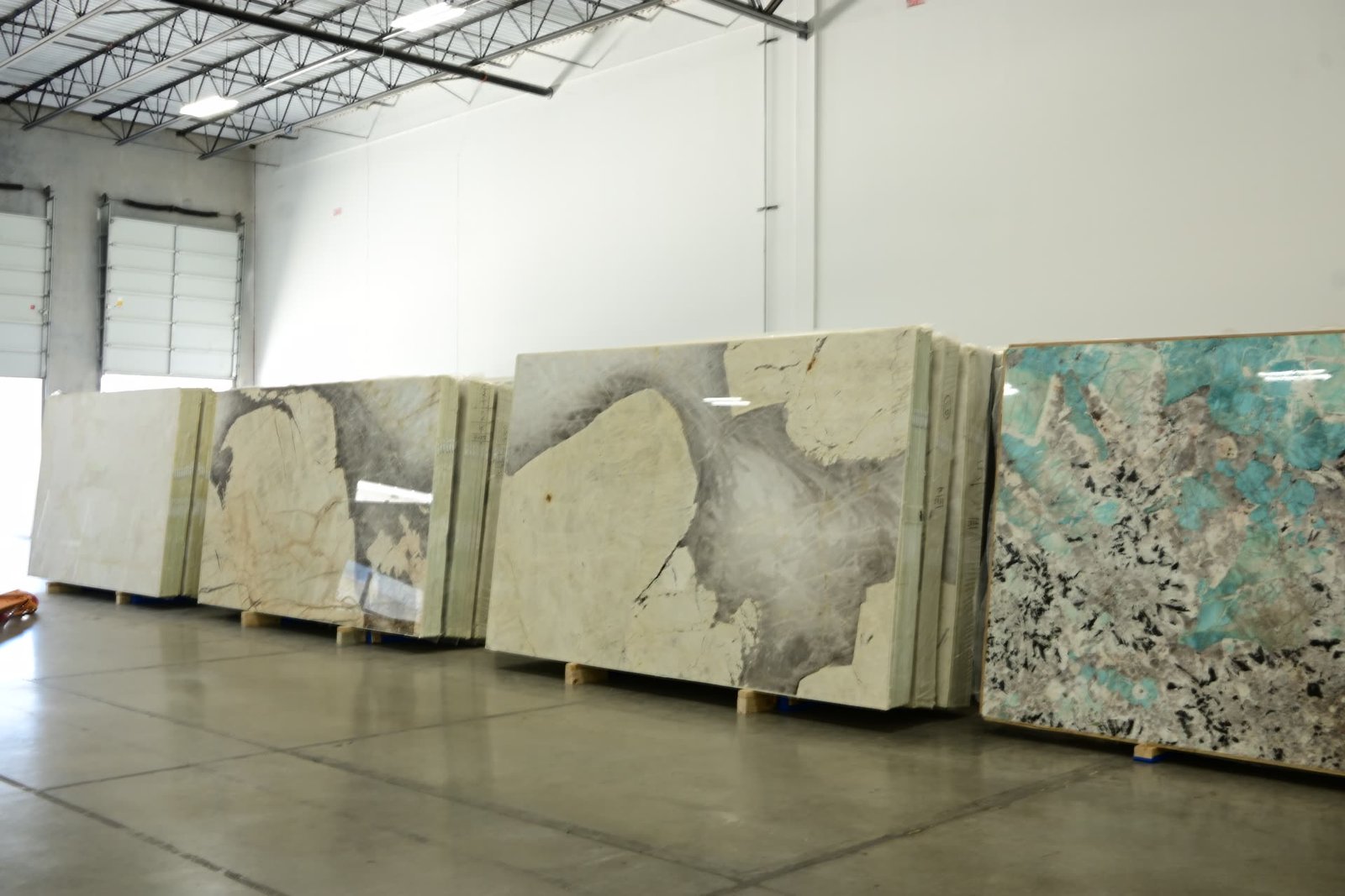 A row of stone slabs standing against a showroom wall in cream, grey and turquoise tones.